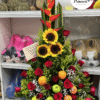 arreglo floral con rosas, girasoles, heliconias y frutas frescas