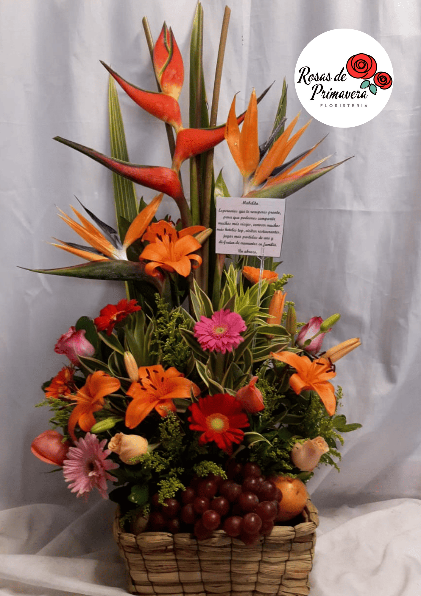 arreglo floral con rosas, gerberas, lirios y frutas